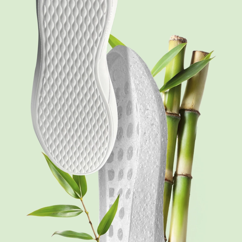 Solados em EVA branco posicionados ao lado de hastes de bambu e folhas verdes, ilustrando o compromisso com sustentabilidade.