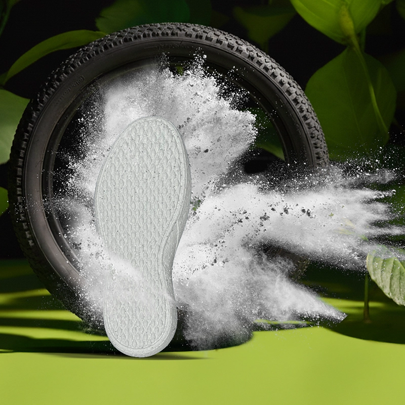 Solado em EVA branco em destaque à frente de pneu reciclado e partículas de pó, simbolizando inovação, sustentabilidade e eficiência tecnológica nos processos produtivos do setor calçadista.